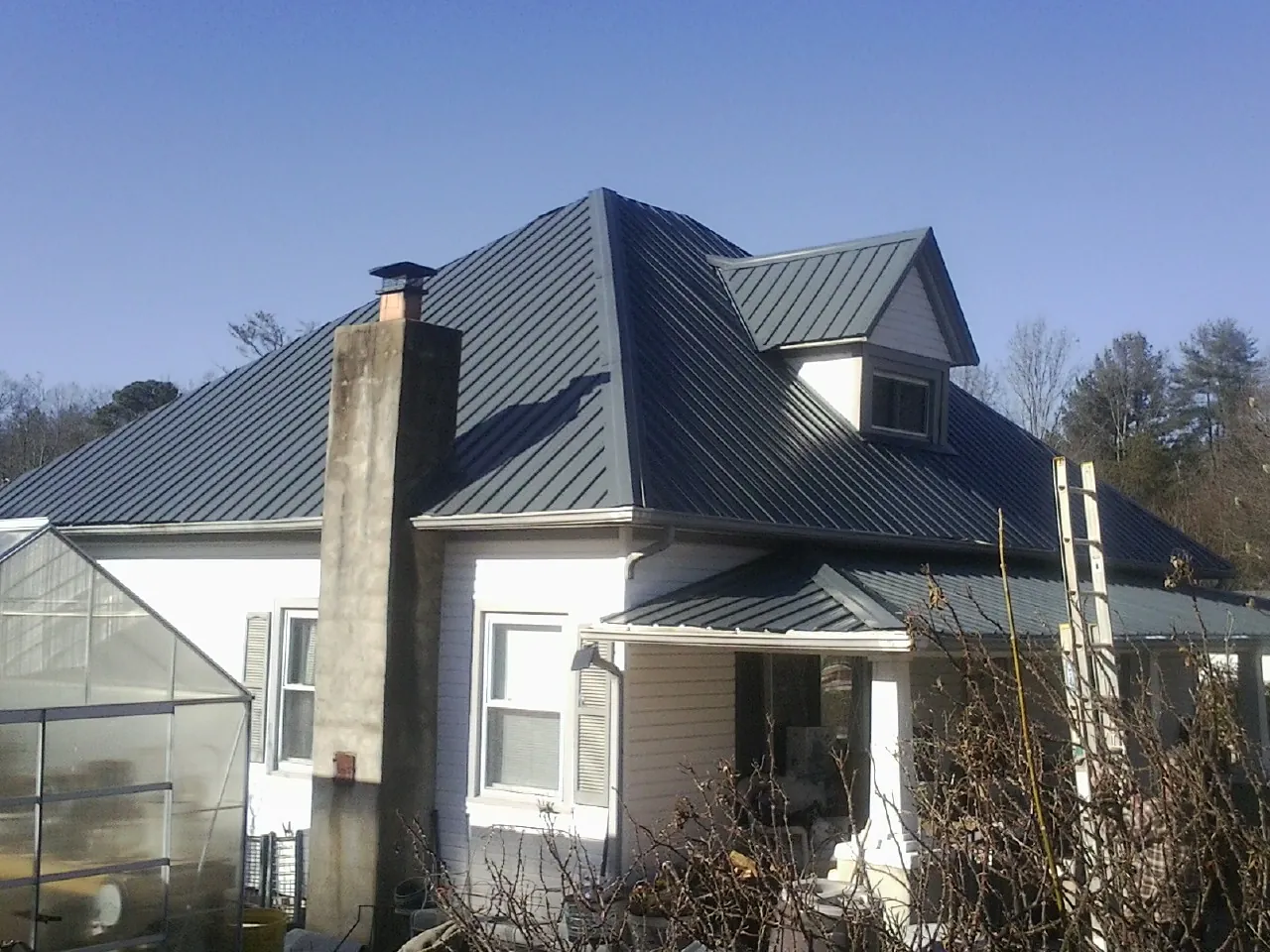 Dark blue standing seam metal roof on a white farmhouse with dormer — Slate & Tile Roof Repair by Roofing Brothers in Hartville