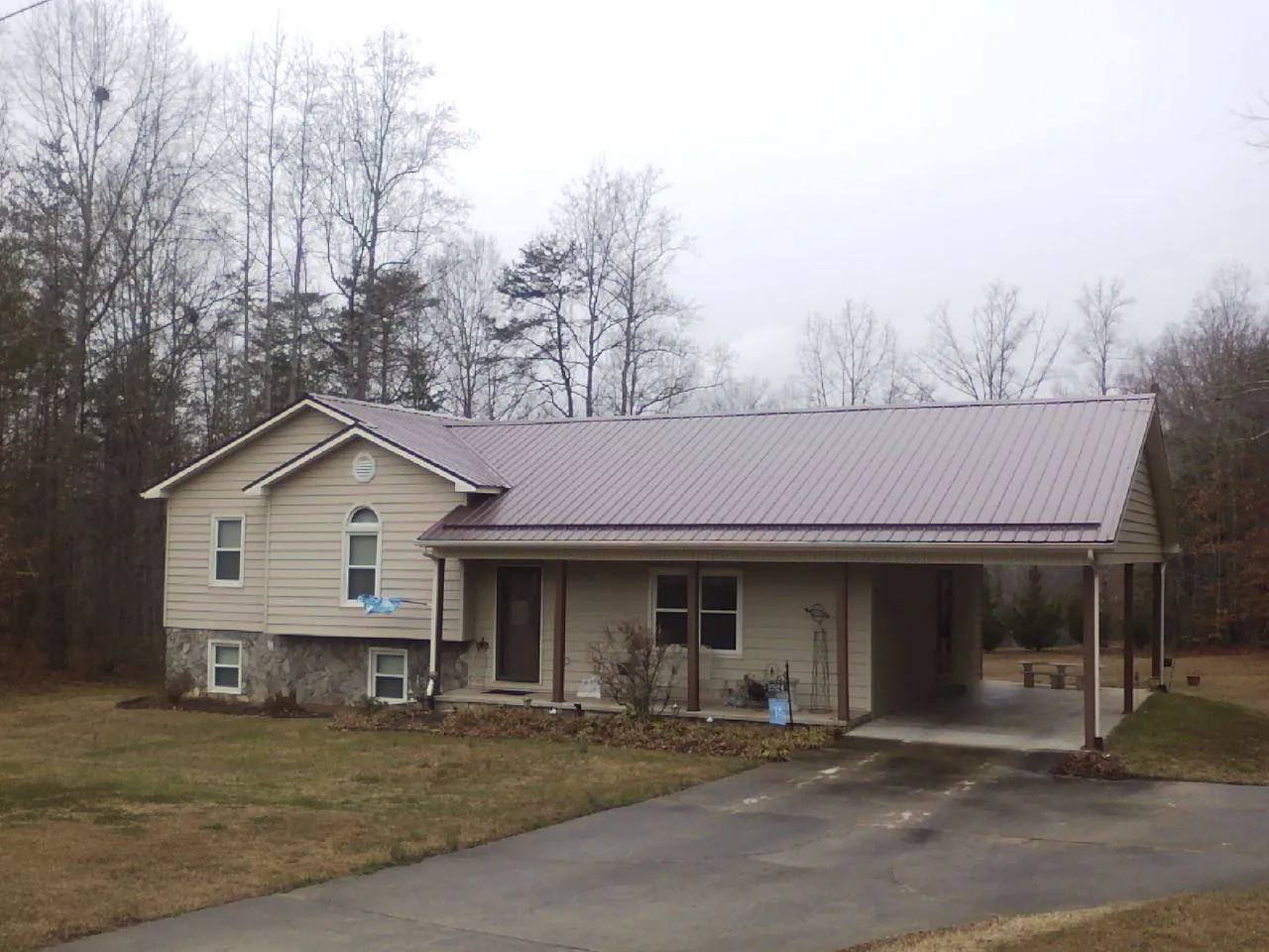 Burgundy metal roof on a tan split level home with an attached carport in Hartville