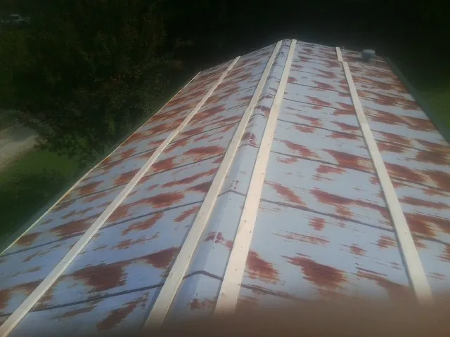 Rusted metal roof panels with new wood purlins before replacement — Storm Damage Roof Repair in Hartville by Roofing Brothers