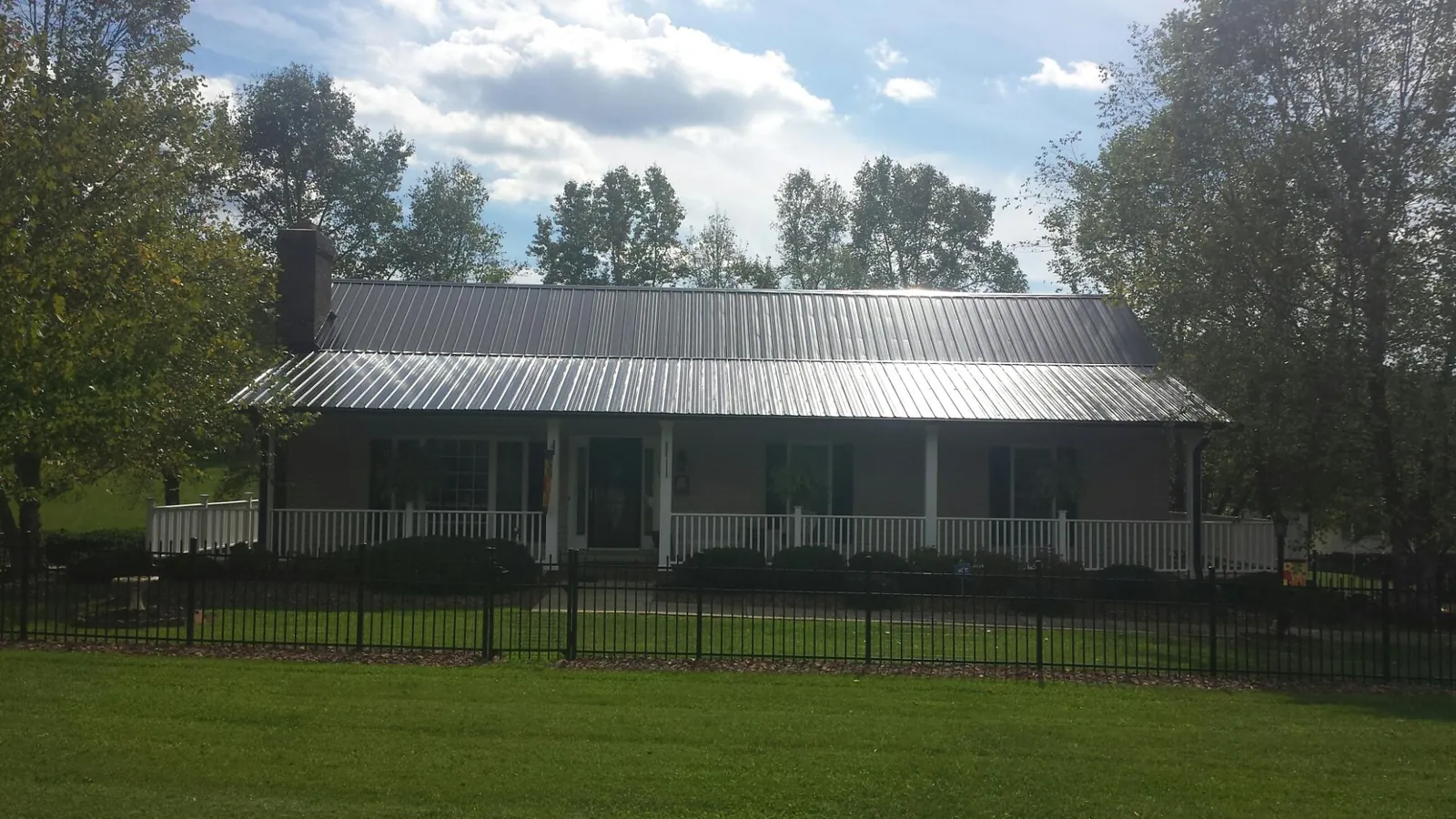 Gray metal roof on a brick ranch with a full width front porch — Gutter Guard Installation work by our crew in Hartville